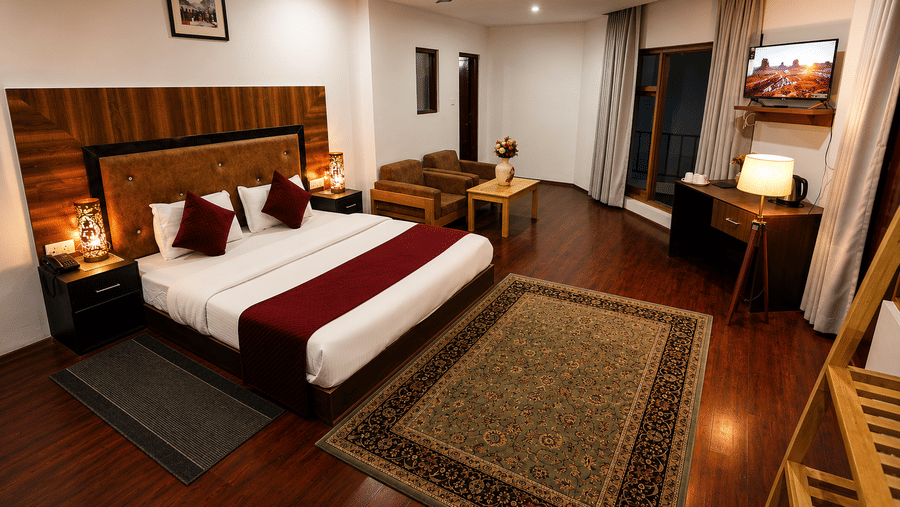 A room with a large bed, pillows, spreads, wall mounted art works, carpets, lamps, and a fan. | Indus Serinity, Leh Ladakh