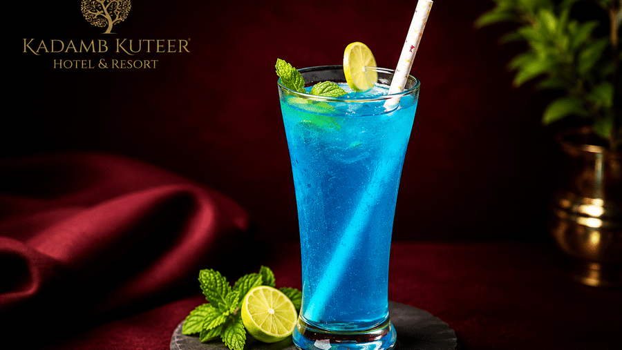 Blue mocktail garnished with mint and a straw on a dark surface at Kadamb Kuteer, Vrindavan.