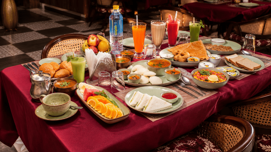 Dining table with a full spread of Indian dishes, beverages, and accompaniments at Kadamb Kuteer, Vrindavan.