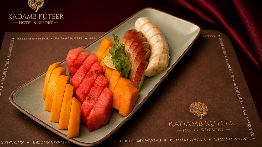 Assorted sliced fruits including watermelon and mango arranged on a white rectangular plate at Kadamb Kuteer, Vrindavan.