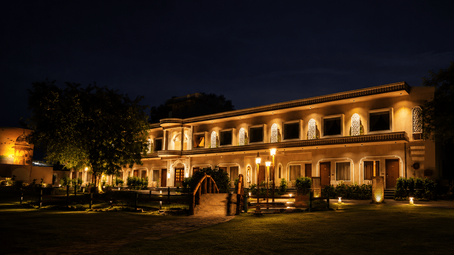 Front facade of the heritage property illuminated at night with warm garden lighting at Kadamb Kuteer, Vrindavan.