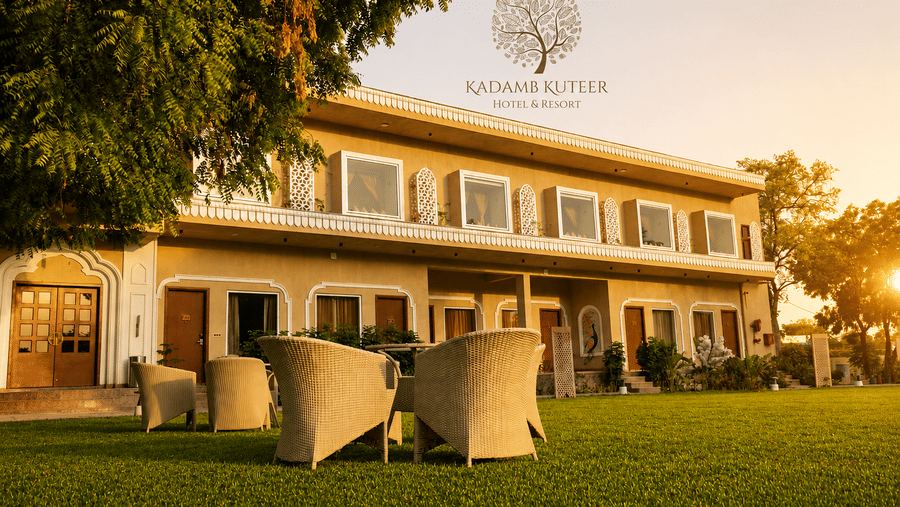 Property exterior with outdoor wicker seating, trees, and warm golden hour lighting at Kadamb Kuteer, Vrindavan.
