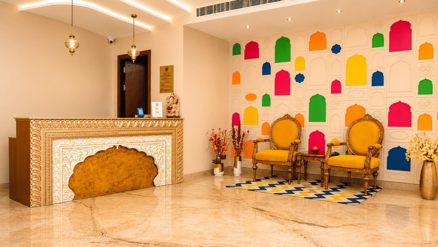 Reception desk with marble flooring, golden chairs, and colourful lantern wall art at Kadamb Kuteer, Vrindavan.