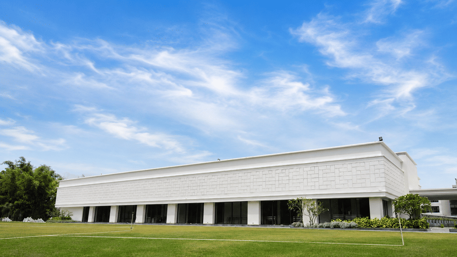 Exterior view of the modern white building and manicured green lawn at Kiranshree Grand Hotel.