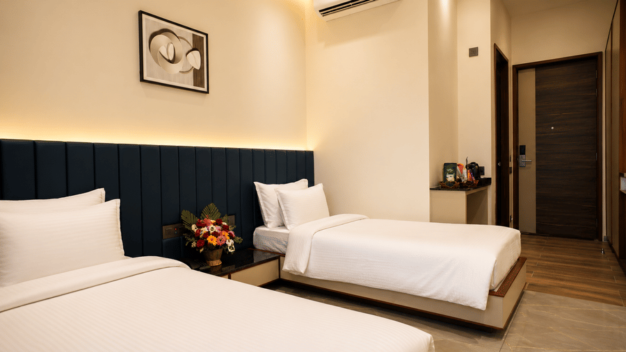 Deluxe Twin Room at Lords Swastik Studio, Kodinar featuring two single beds, contemporary interiors, air conditioning, elegant lighting, and modern in-room amenities for a comfortable stay.