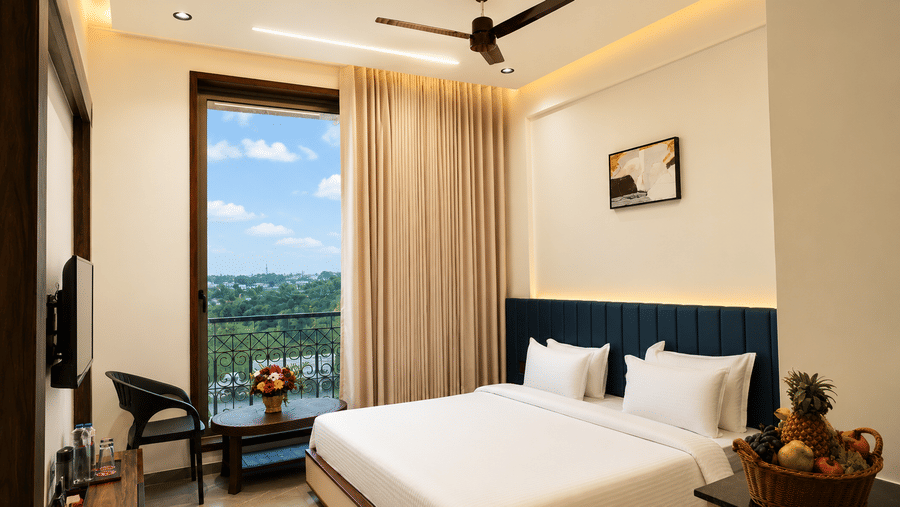 Deluxe King Room at Lords Swastik Studio, Kodinar with a king-size bed, modern interiors, large window overlooking scenic views, work desk, and premium amenities for a relaxing stay.