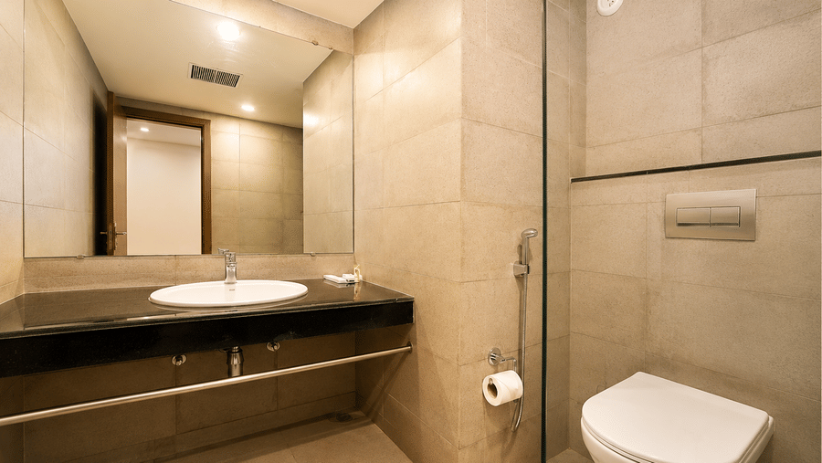Contemporary bathroom featuring a vanity, wash basin, and toilet at Max Hotel Jabalpur.