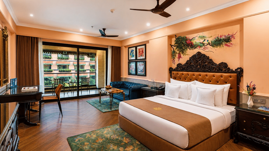 A large bed and sofa with a balcony in a Premium Pool View Room at MAYFAIR Bay Resort, Paradeep.