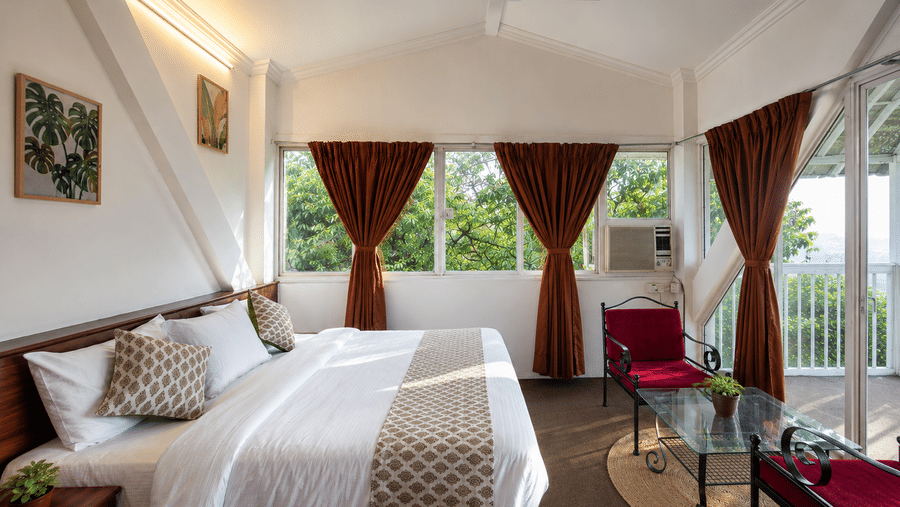 Double bed with patterned runner and cushions beside brown curtains and balcony doors in a Wind Chalet bedroom.
