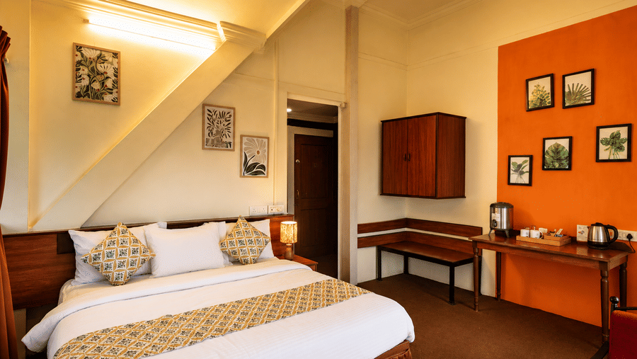 Full room view at Wind Chalet with a king double bed, slanted ceiling beam, orange feature wall, and wooden furniture.
