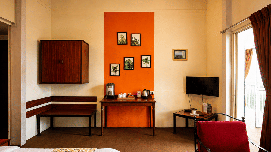 Guest suite at Wind Chalet with red armchair, television area, orange feature wall, and corner bench workspace.