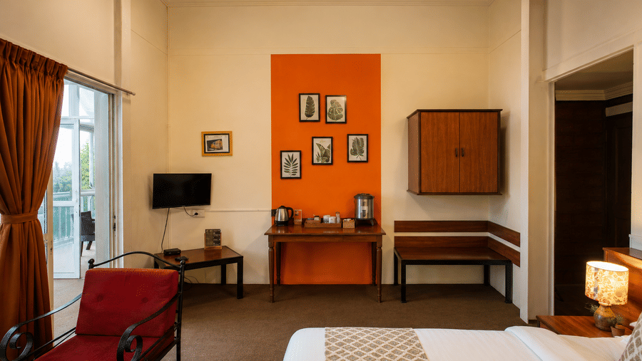 Guest room at Wind Chalet with white bed, orange feature wall displaying frames, red armchair, and bench seat.
