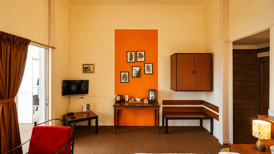 Interior room view at Wind Chalet showing an orange feature wall with picture frames, television, and seating.