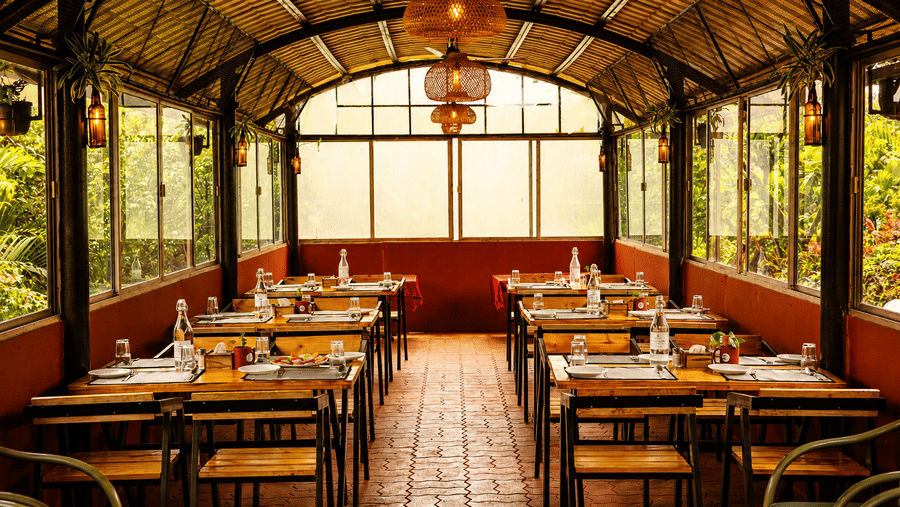 Symmetrical view down the central aisle of Wind Chalet restaurant showing set tables under a vaulted bamboo ceiling.