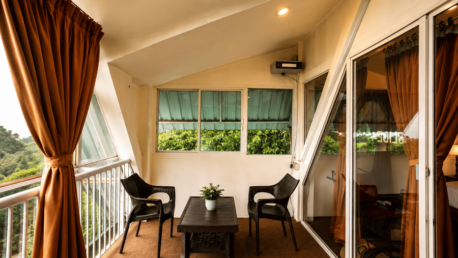 Covered terrace at Wind Chalet with black seating, coffee table, brown drapes, and glass doors looking outside.