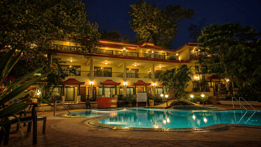 The swimming pool of the hotel with the hotel building at the background, with all the outdoor lights switched on during night time.