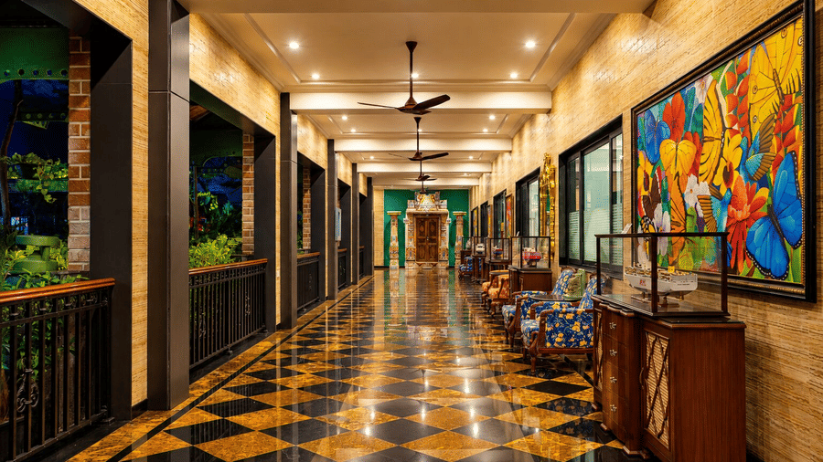 A hallway with tiled floors, wall art, and seating lined along glass windows at MAYFAIR Bay Resort, Paradeep.