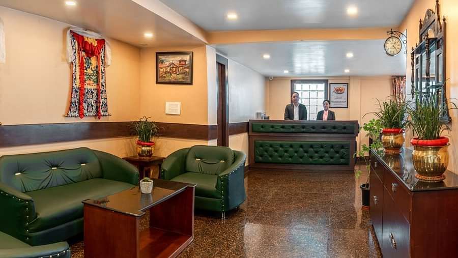 A sofa set and coffee table in the reception area that has a person standing at a desk | Summit Oakden Resort & Spa, Mall Road