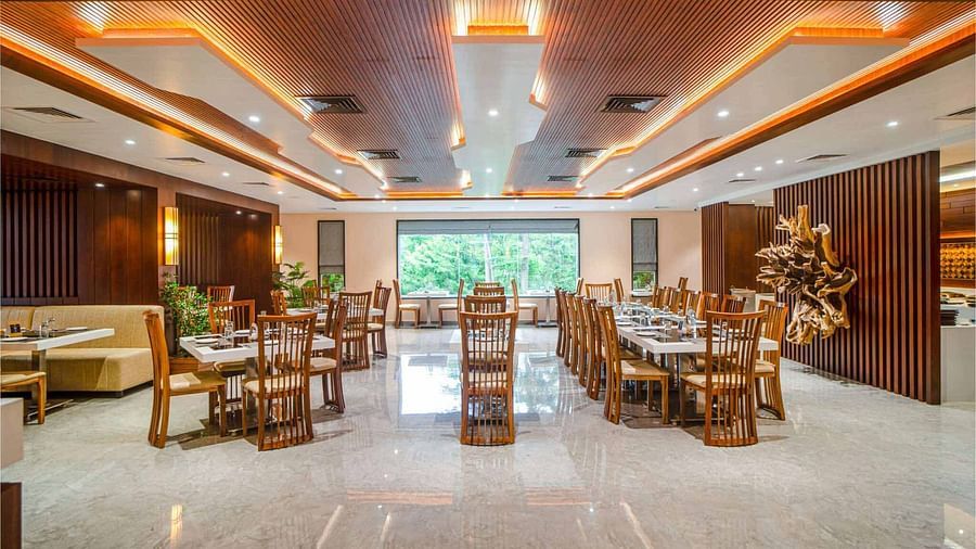 The well-lit dining area at Mansha Palace in Port Blair features neatly set tables and comfortable wooden chairs.