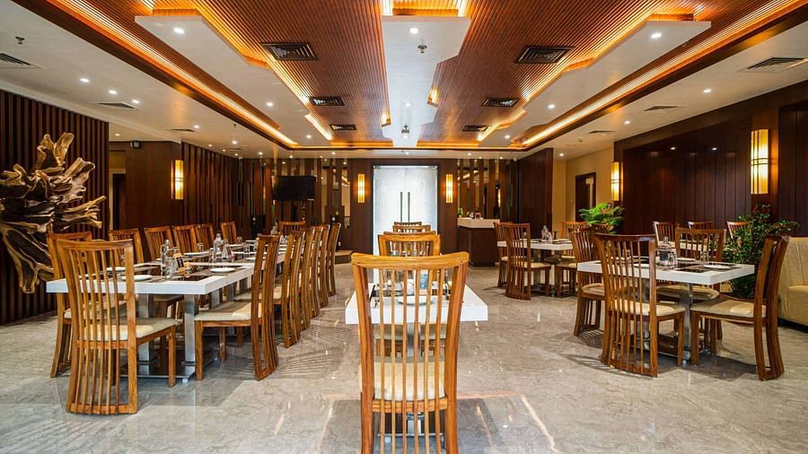 The spacious dining hall at Mansha Palace is furnished with numerous set tables and comfortable wooden seating.