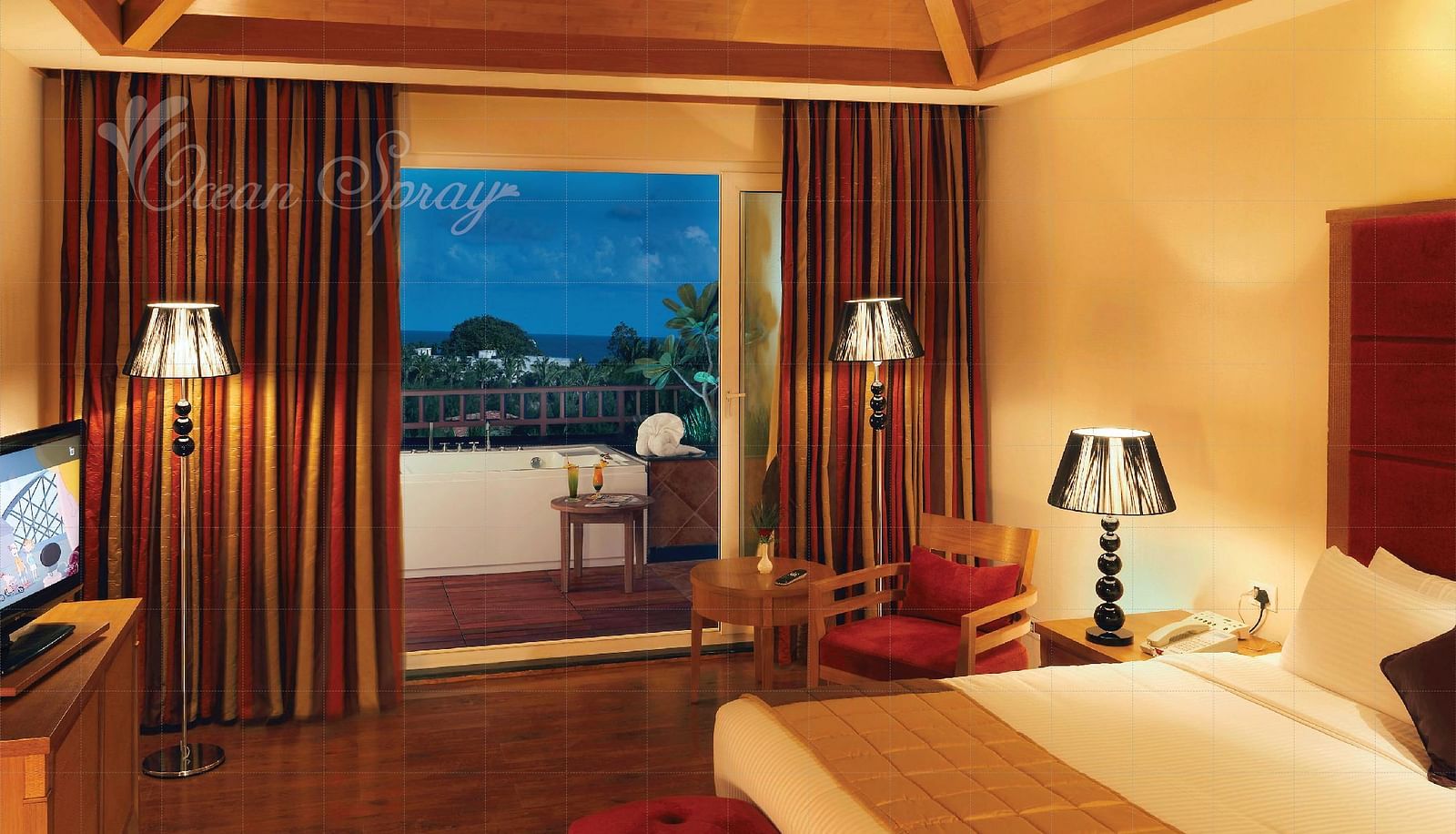 a double bed with side lamps and a tv opposite the bed inside Heavens at Ocean Spray, Puducherry.