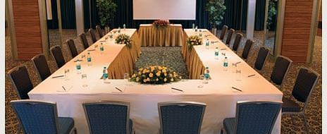 Shot of the expansive conference room in Mirage Hotel featuring a large table with chairs around it along with a projector on the wall. | Mirage Hotel