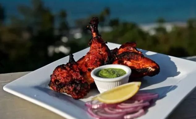 Plate of grilled tandoori chicken with onions, lemon, and chutney in front of ocean | A Stone's Throw Away