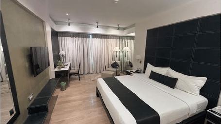 Contemporary room at Mirage Hotel with black tufted headboard, wood flooring, and work desk.