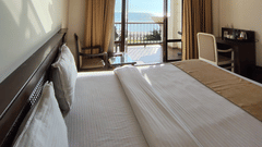 A spacious room at VITS ExcellenSea, Dapoli, with a king-sized bed, a seating area, and a balcony overlooking the ocean.