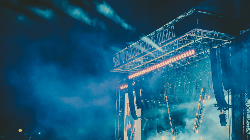 Open-air concert stage lit up at night with a cheering crowd in front