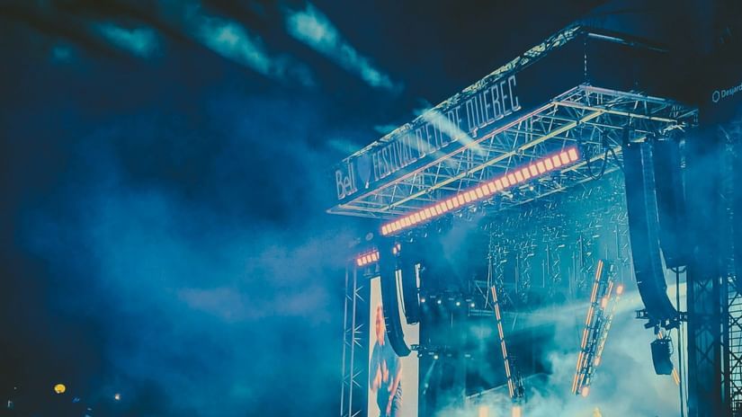 Open-air concert stage lit up at night with a cheering crowd in front.
