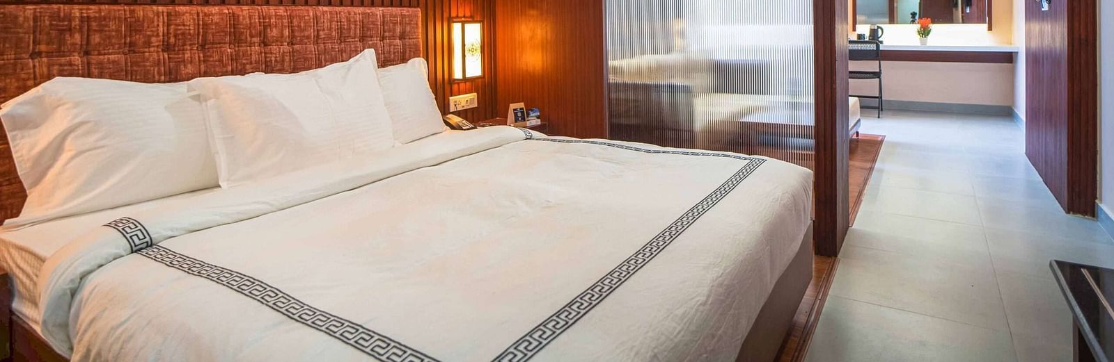 A stylish bedroom at Mansha Palace features a comfortable bed and a partial view into an adjacent area with a desk.