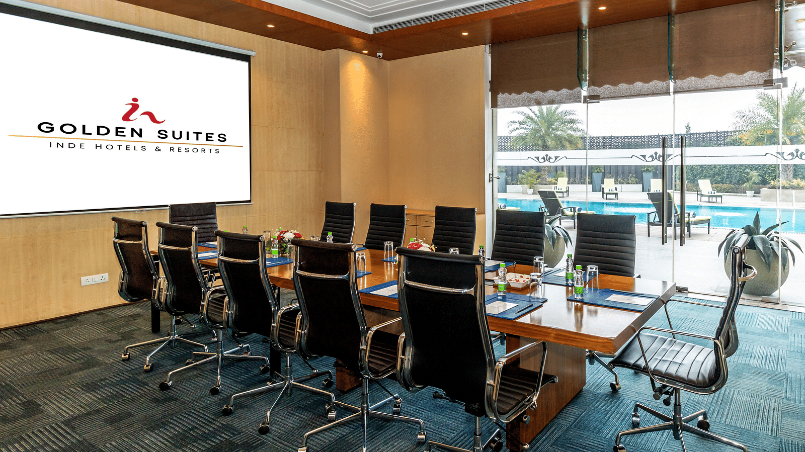 Boardroom with chairs round the table and a screen at Golden Suite