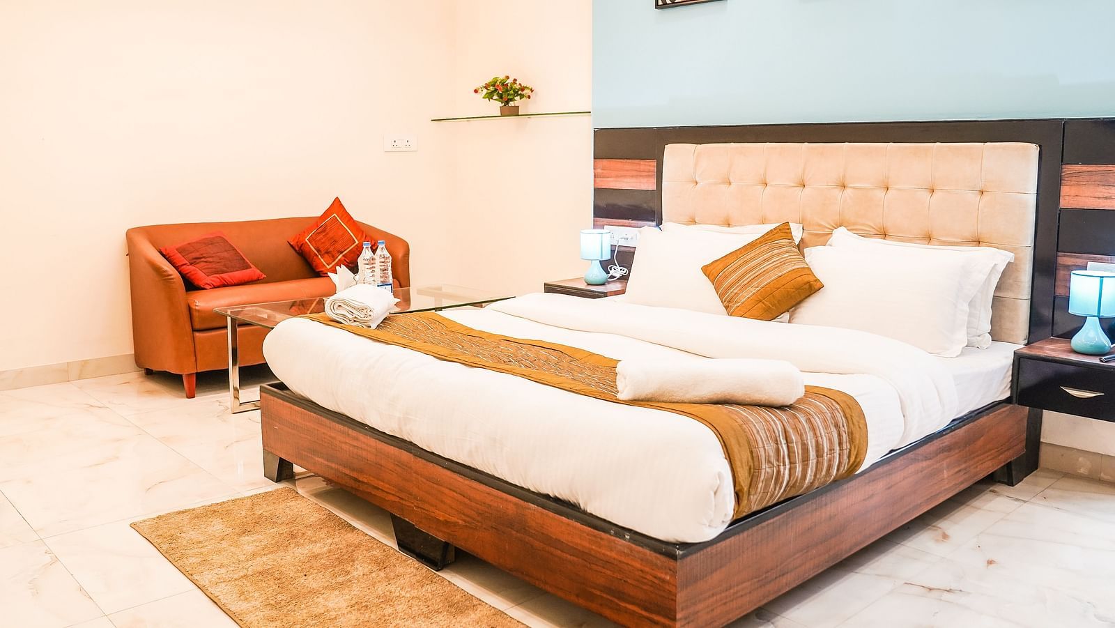 A neatly arranged room features a double bed with patterned bedding, a chair, and framed pictures on the wall - Asian Suites Cyber Park, Gurgaon