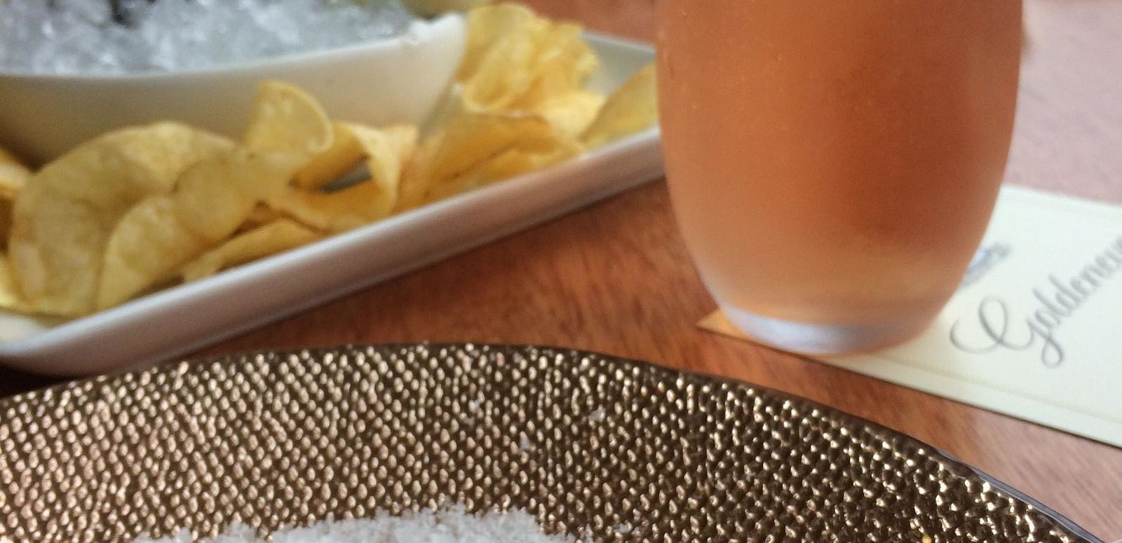 A close-up of a luxurious caviar serving with chips and a glass of rosé at a fine dining restaurant.