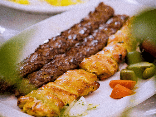 Chelo kebab served on a plate with grilled capsicums served  in traditional manner.