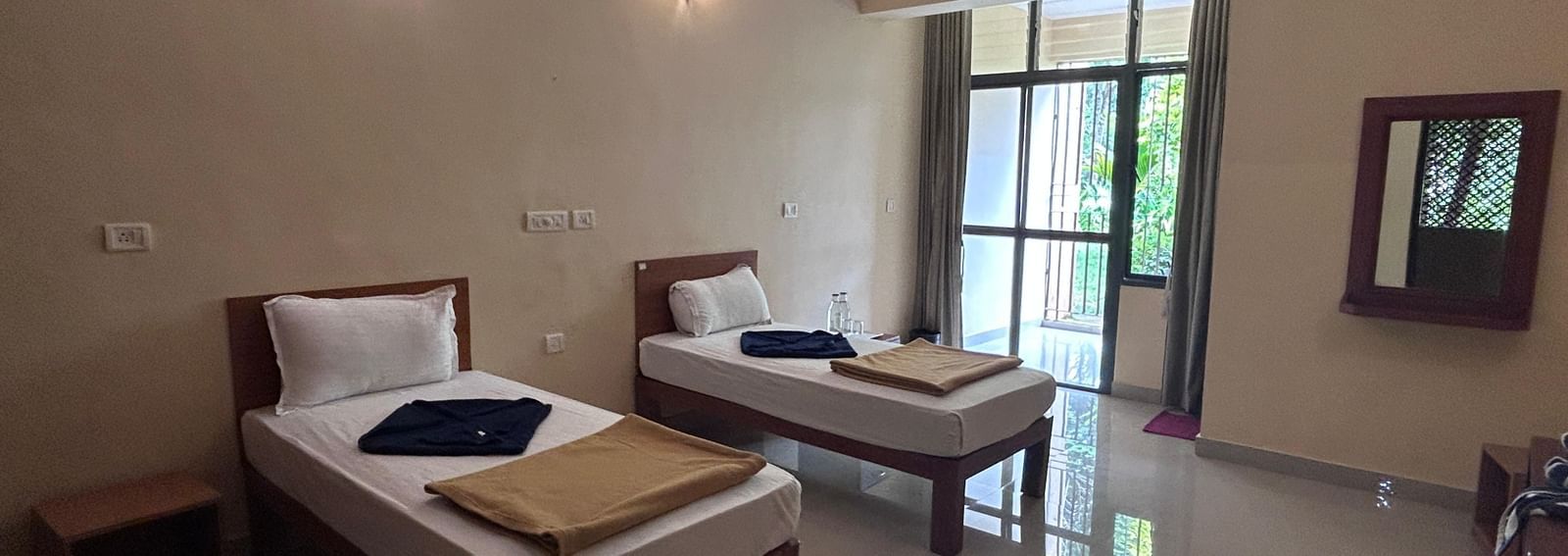 A clean, comfortable twin room at Paradise Wild Hills Resort, Kollur, with two single beds and a balcony.