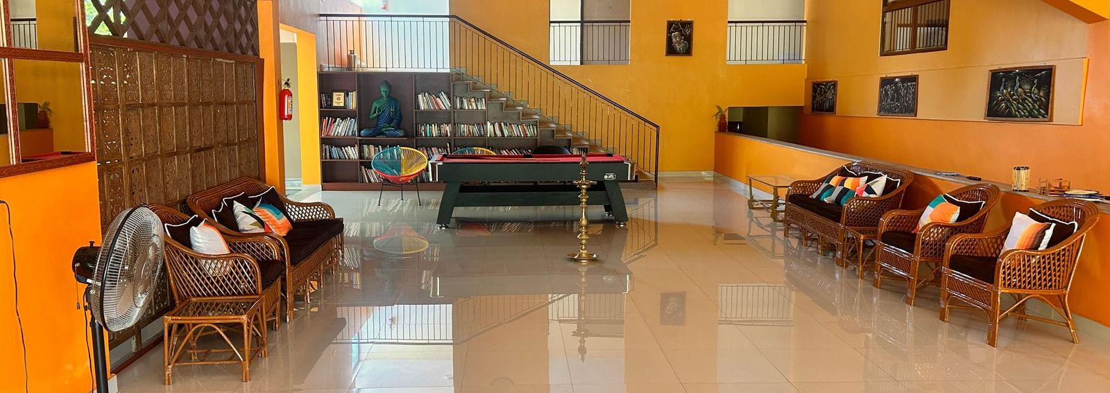 The recreation area at Paradise Wild Hills Resort, Kollur, with a pool table, staircase, and comfortable rattan furniture.