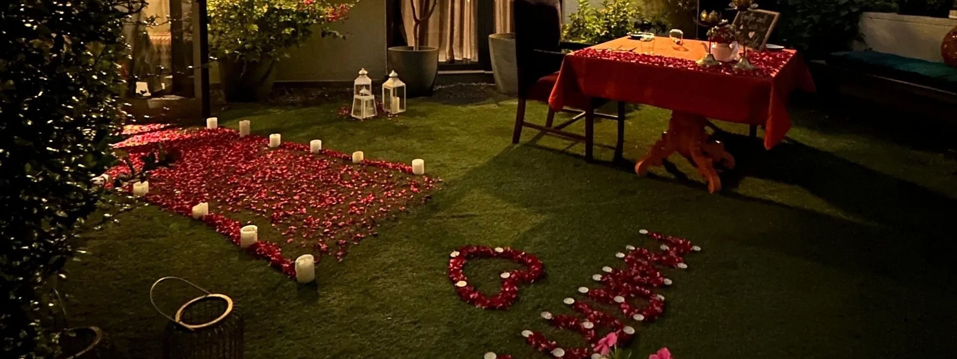 Garden setup with tables, chairs, and rose petals arranged for an outdoor evening celebration beside a house at Karma Chalets. 