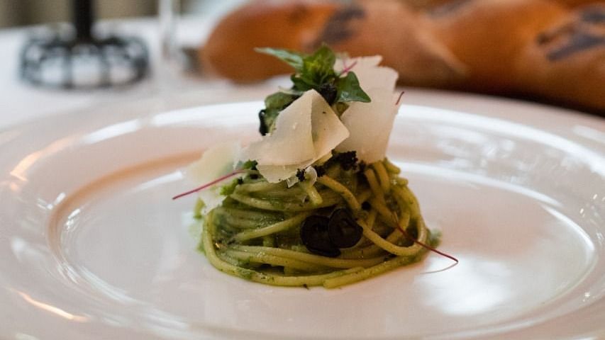 image of pesto pasta served at the sevilla topped with fresh cheese - The Claridges New Delhi