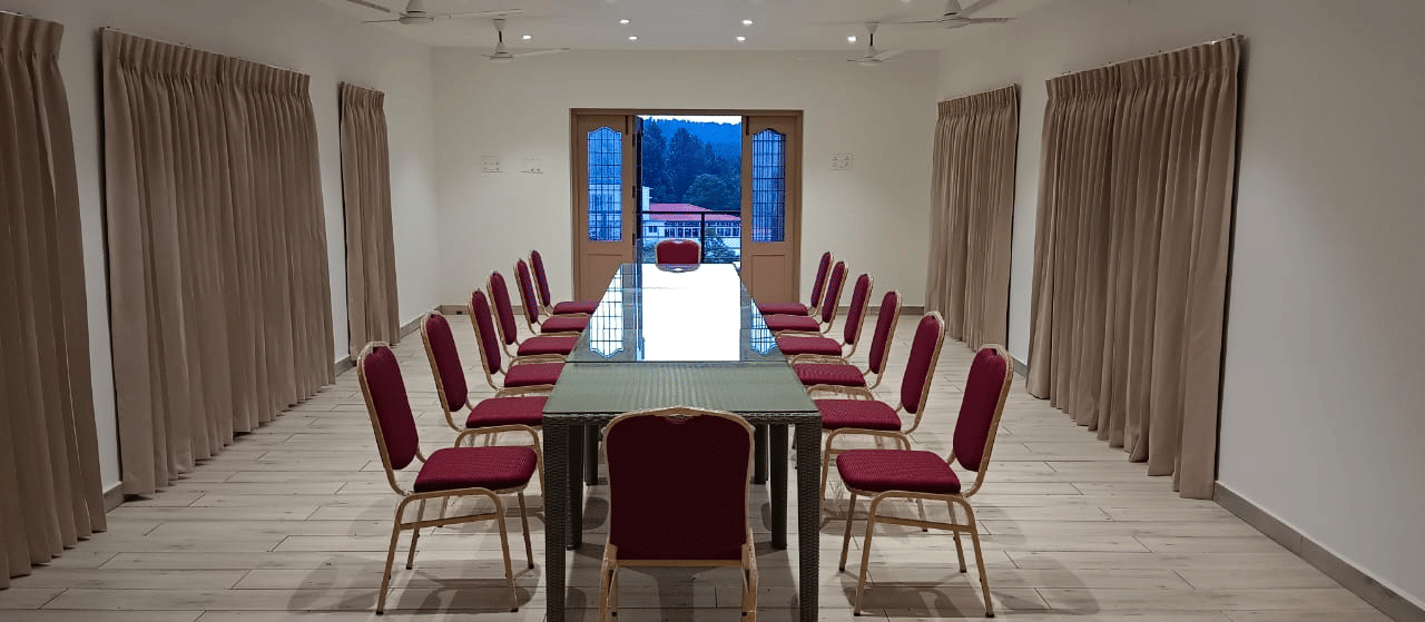 Front-view shot of the Green Park hall with chairs and tables arranged in boardroom setting at WOW Naturefull Resorts.