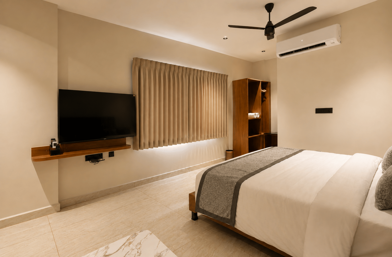 Modern guest bedroom at Essentia Residency, Tirupati featuring a king bed, wall-mounted TV console, air conditioning, and wardrobe.