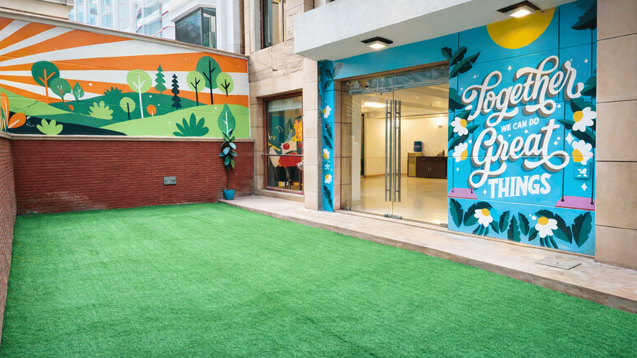 An open lawn space with green flooring and wall art, at EMBLEM - Arjun Marg, Golf Course Road, Gurgaon.