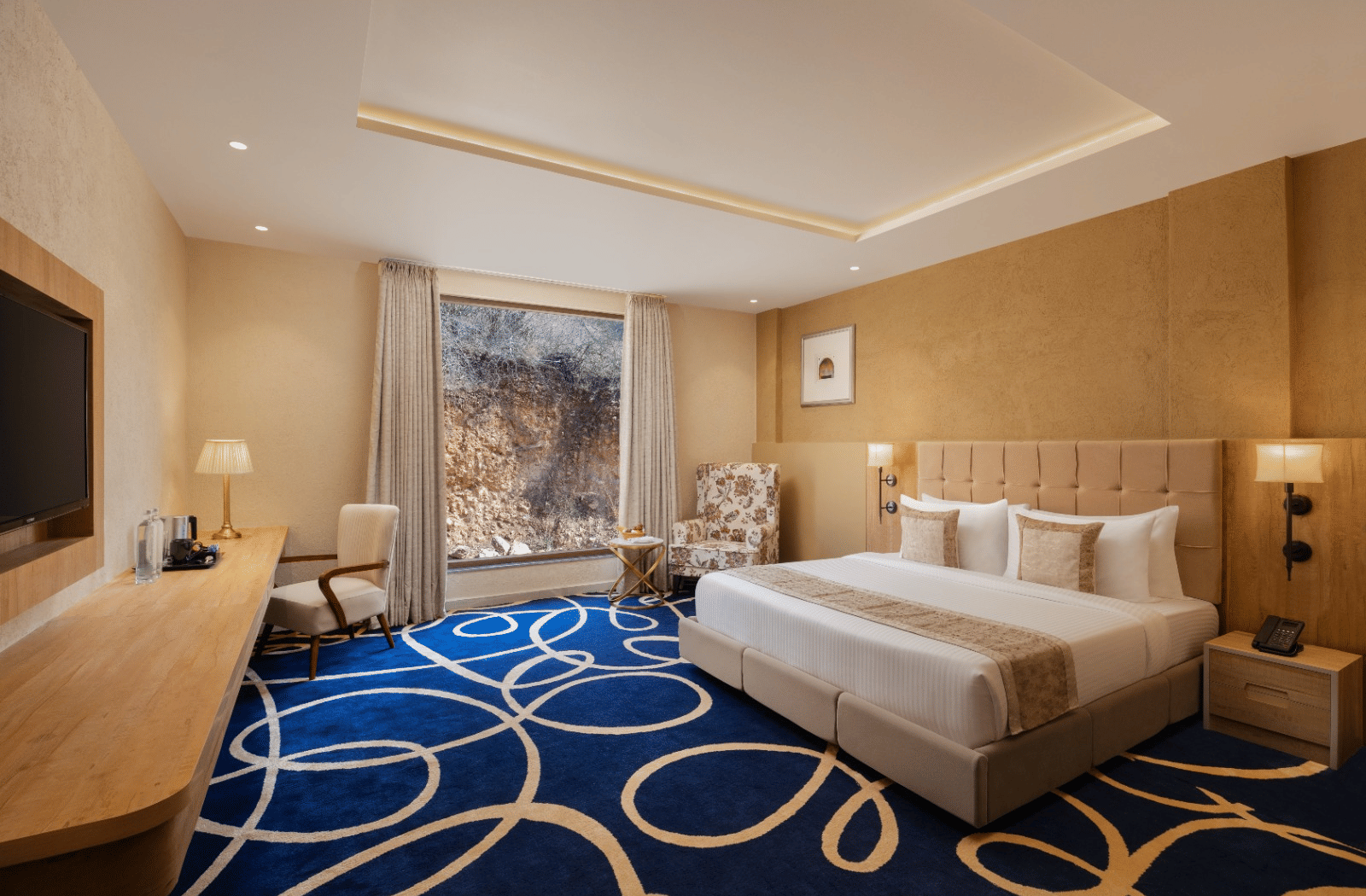 Superior room with king bed and blue accent rug at Essentia Luxury Resort & Spa, Udaipur.