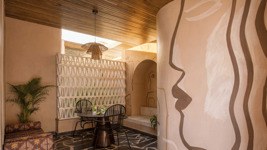 A dining nook at The Sierra - By The Lake featuring a small round dining table, wooden chairs, and a large wall line mural depicting a face profile.