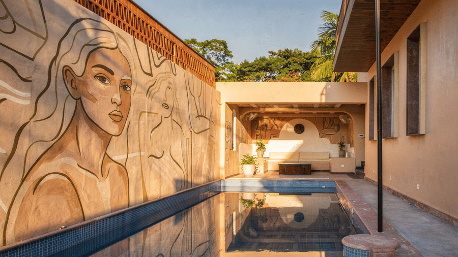 A swimming pool at The Sierra - By The Lake featuring a long outdoor plunge pool, a large detailed wall mural of a woman, and a covered lounge area.