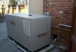 Image of a generator with a brick wall behind.