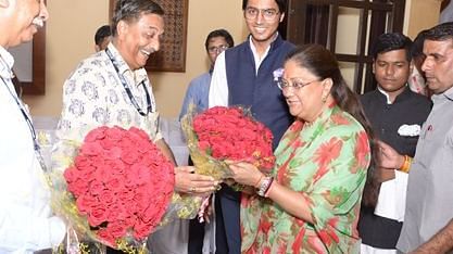A woman being greeted with large bouquets of red flowers in a formal setting