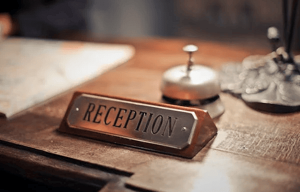 A photo of a table featuring a nameplate of reciption and a bell on it.