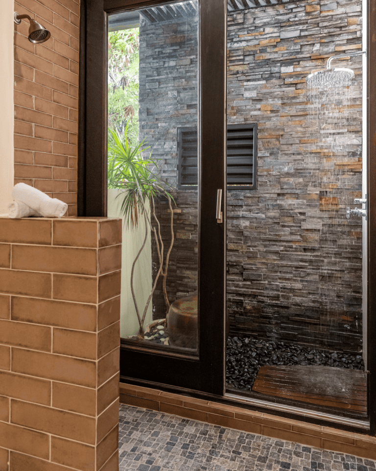 An open shower area surrounded by textured walls and bricks.